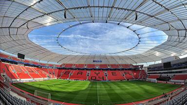 Um estádio grande com um teto curvo e um gramado verde.