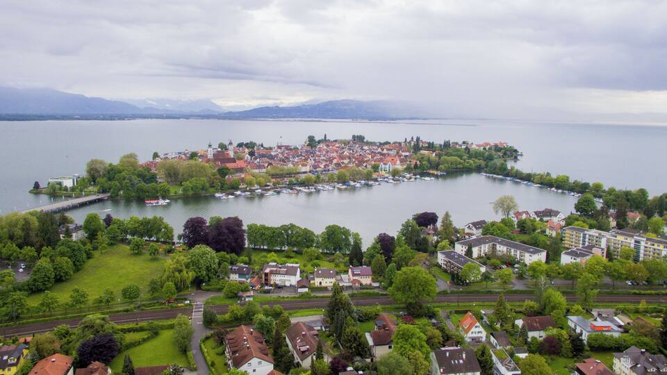 A lakeside town with a central island featuring a church, surrounded by residential buildings and greenery.