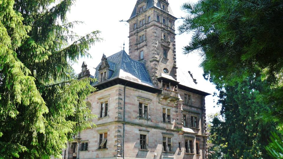 A historic building with a prominent tower and a well-manicured lawn.