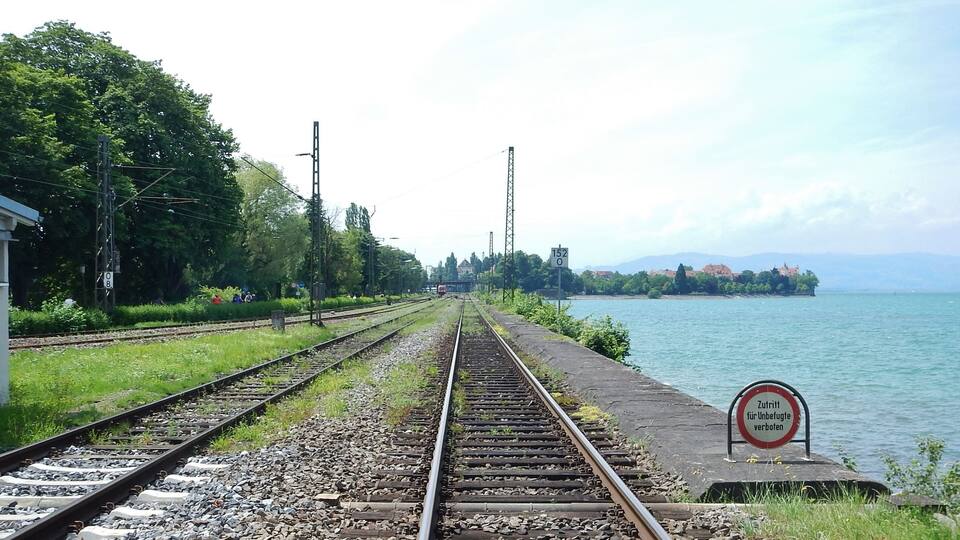 Railway tracks leading to a body of water with a sign prohibiting access.