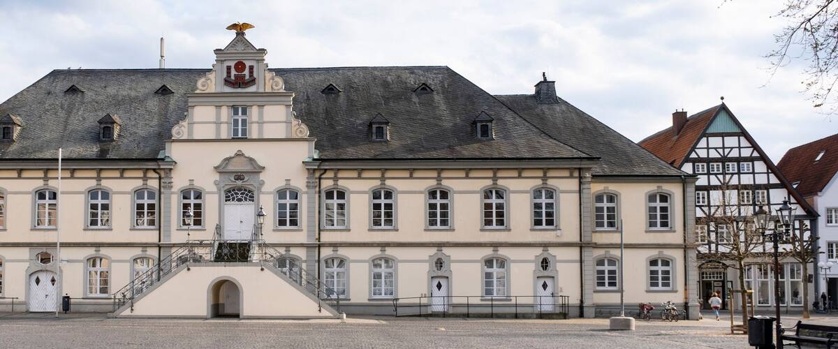 A historic building with a central staircase, multiple windows, and a decorative roof.