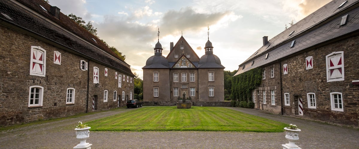 A historic building with a symmetrical facade, a central courtyard, and a cobblestone path.
