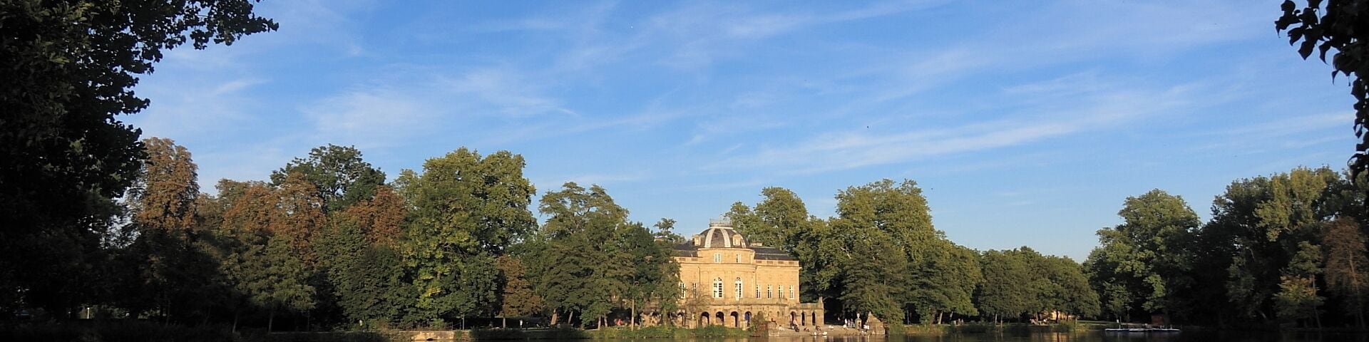 Um lago tranquilo com um edifício histórico rodeado por árvores.