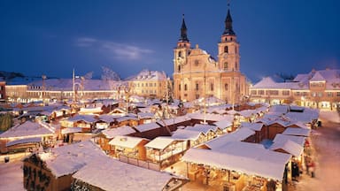A snow-covered market square with historic buildings and a prominent church with two towers.