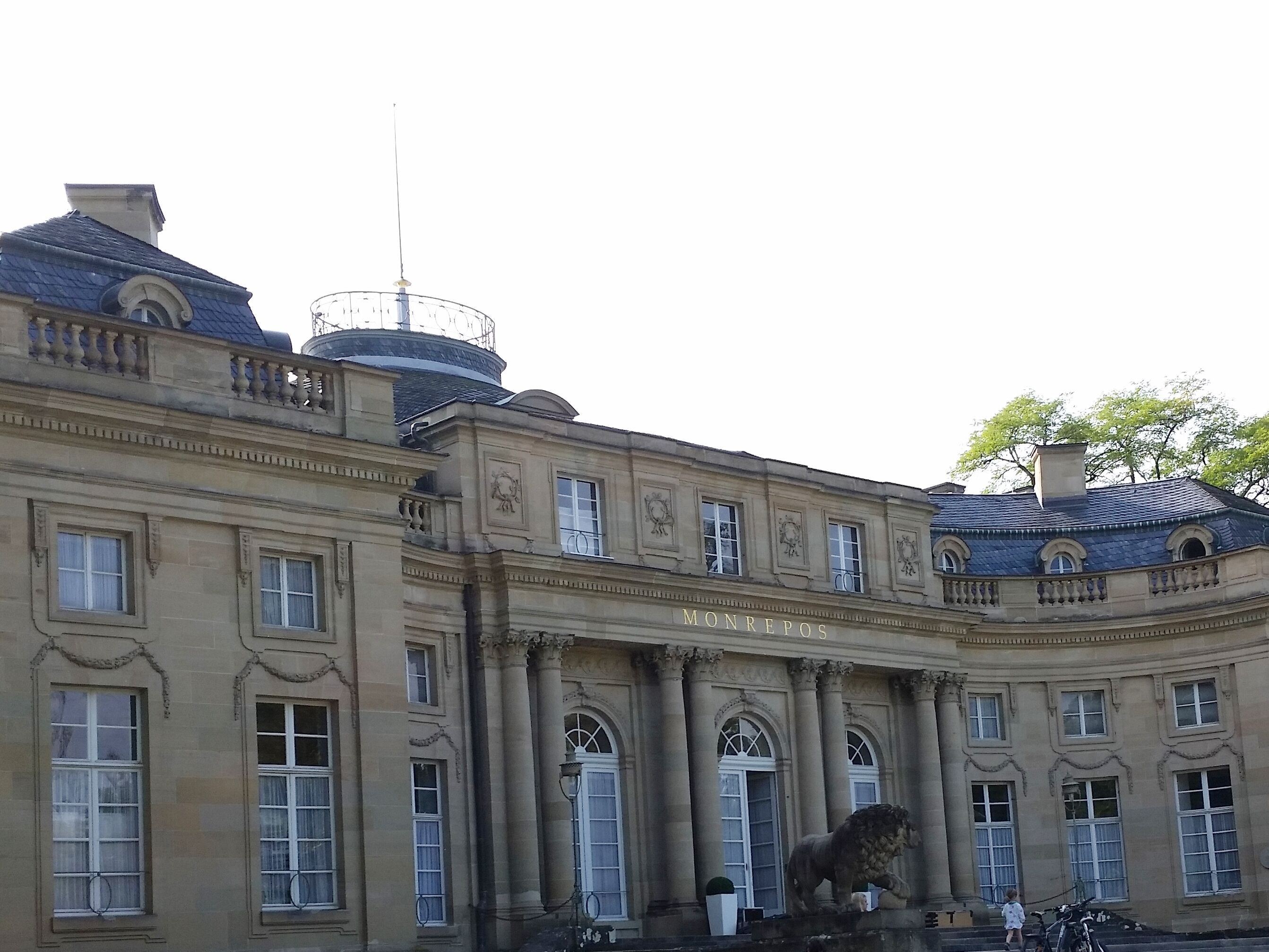 A historic building with classical architecture, including columns and a lion statue.
