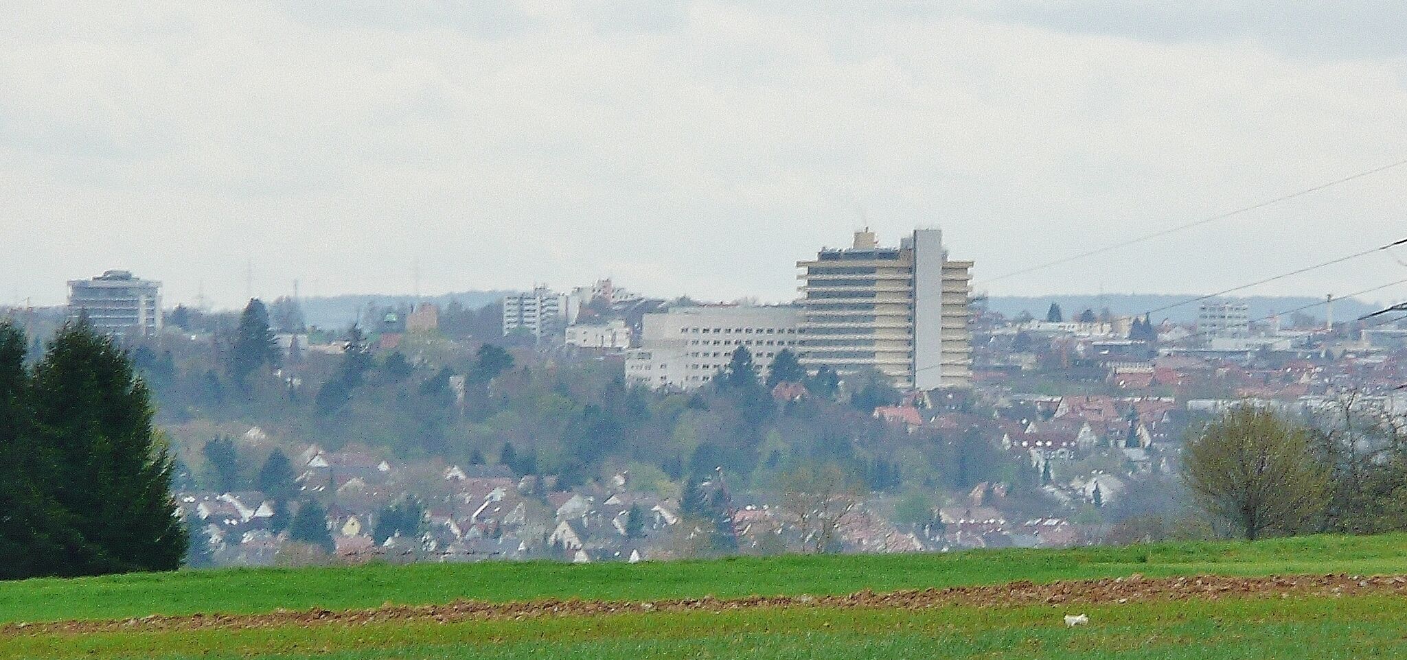 A cityscape with a prominent building in the center, surrounded by residential areas and greenery.