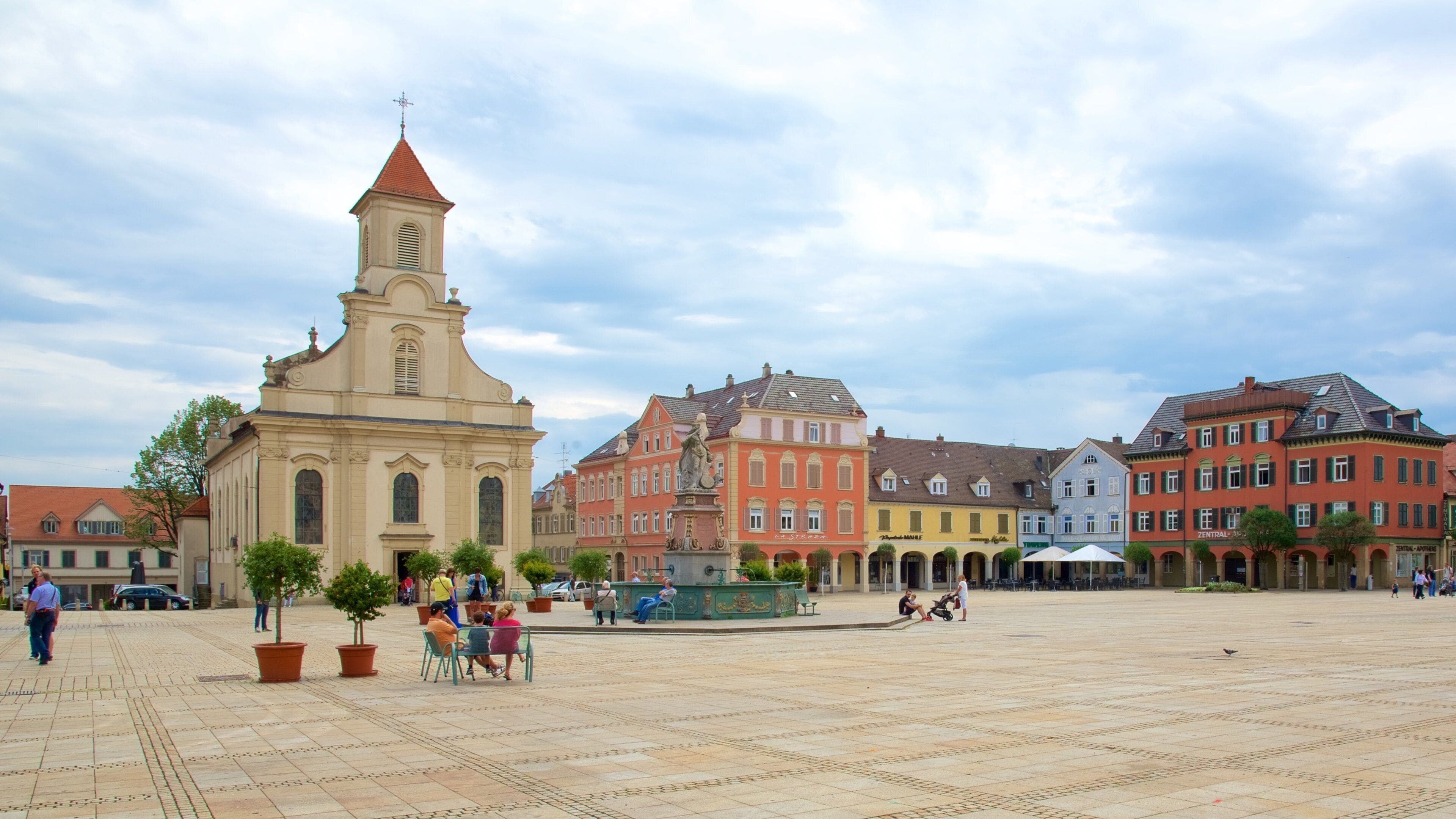 A historic square with a church, colorful buildings, and people.