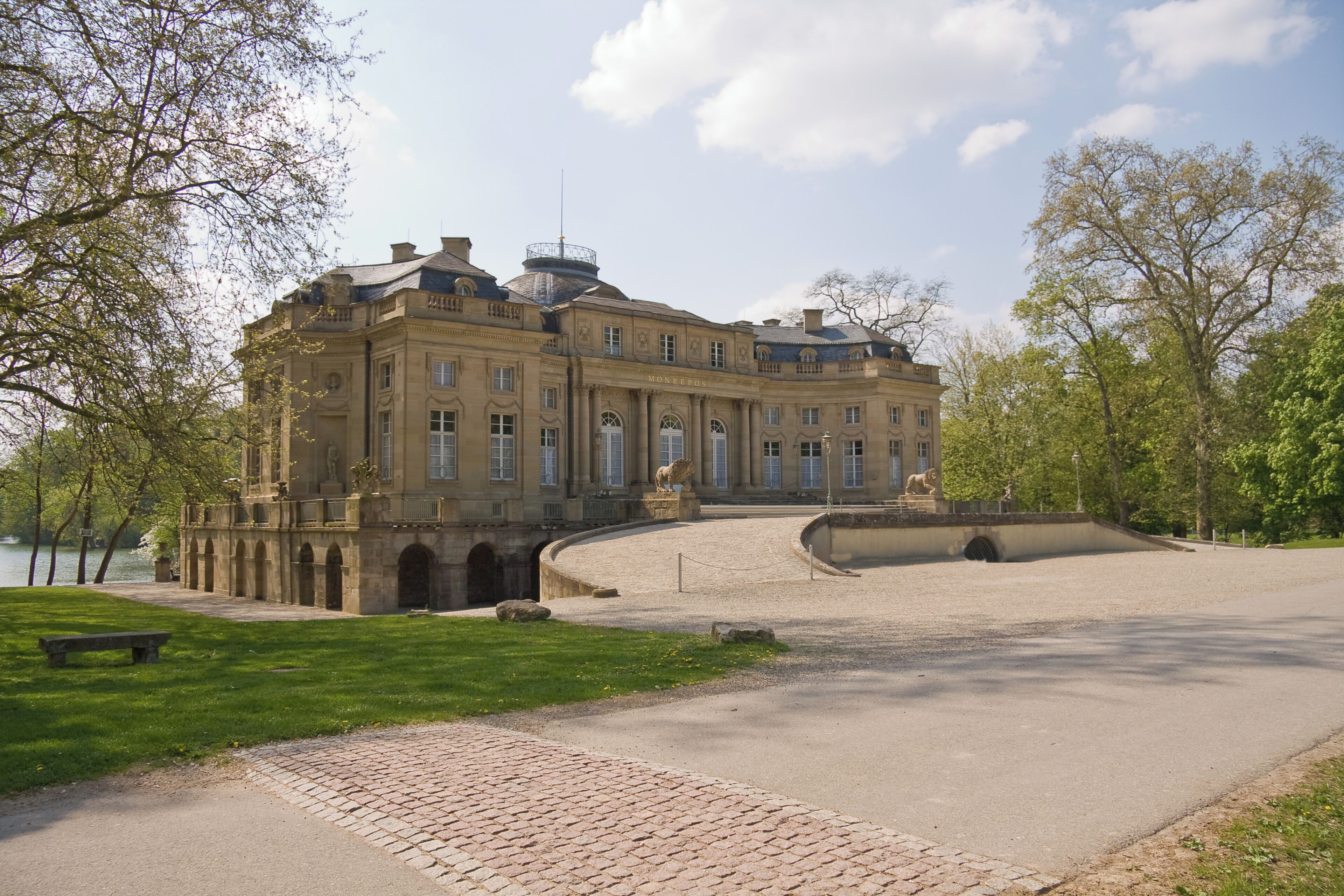 A large historic building with arched windows and a statue in front.