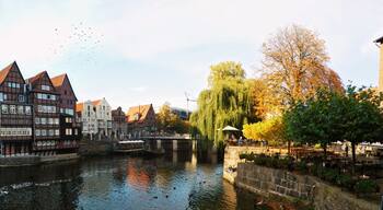 A riverside town with historic buildings, a bridge, and autumn foliage.