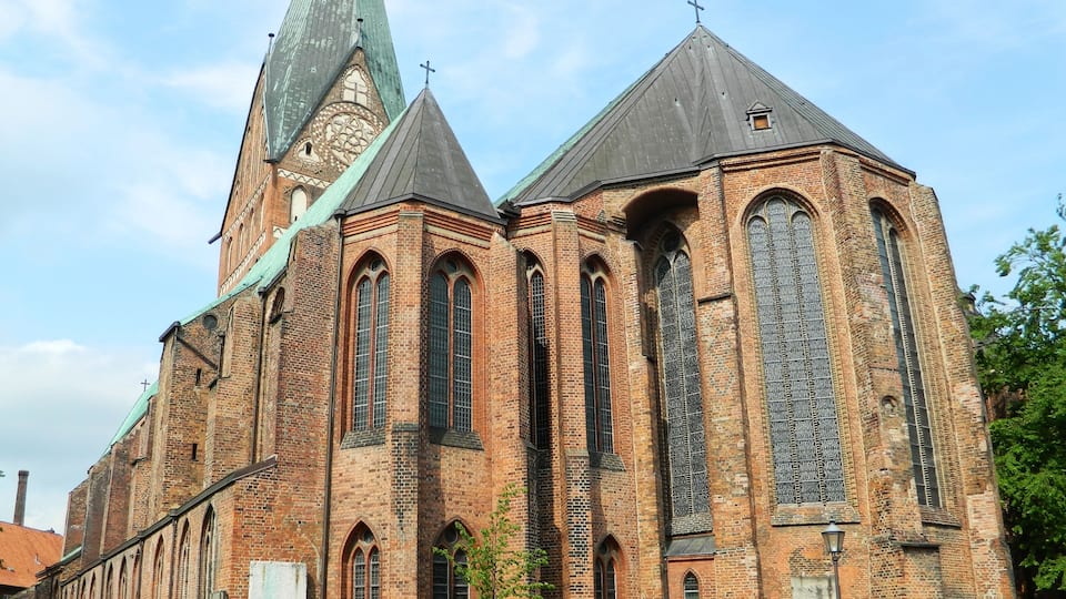 Eine große Backsteinkirche mit einem hohen, schlanken Kirchturm und Rundbogenfenstern.