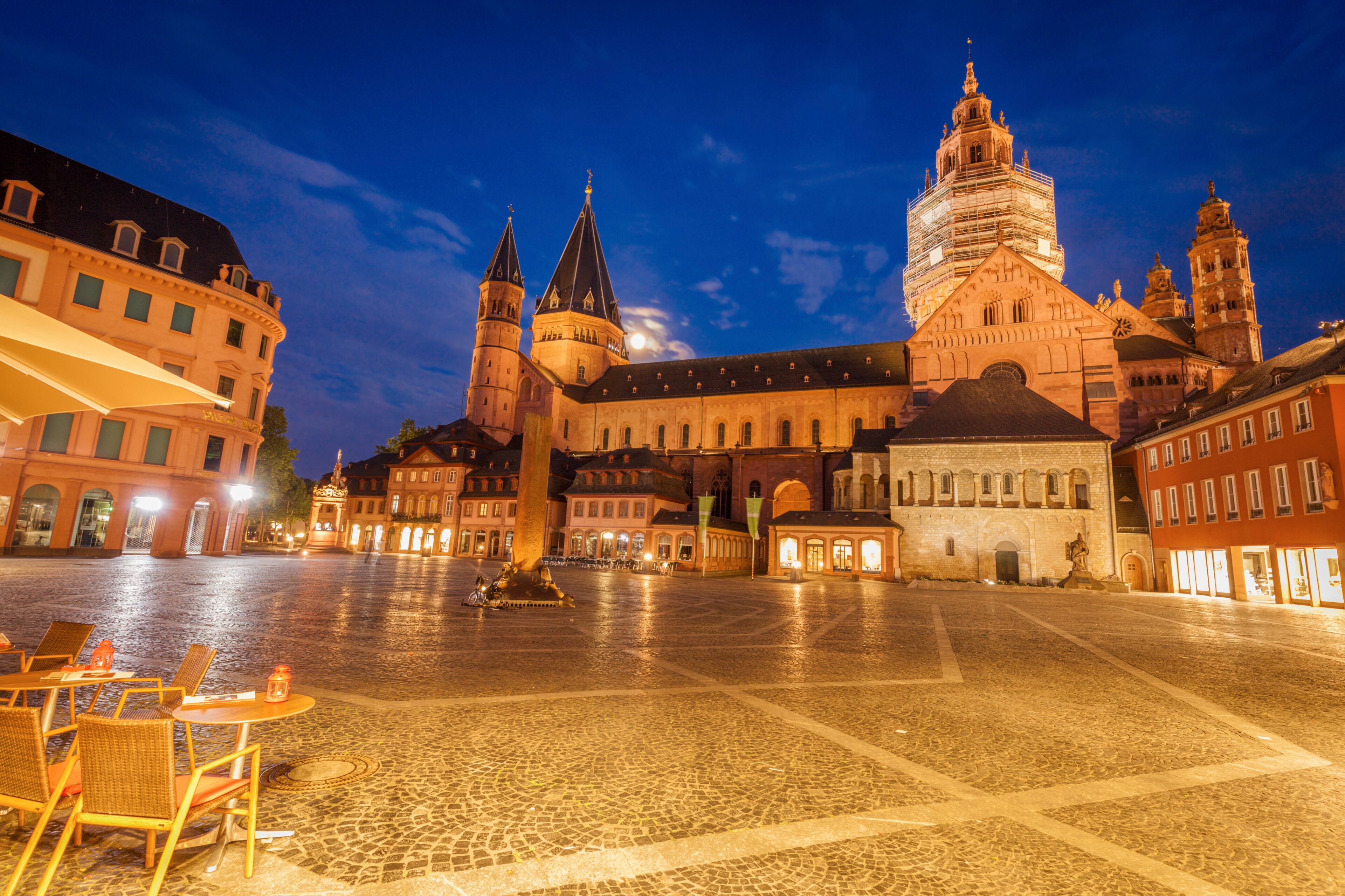 Una plaza histórica con una iglesia destacada, una fuente y un campanario.