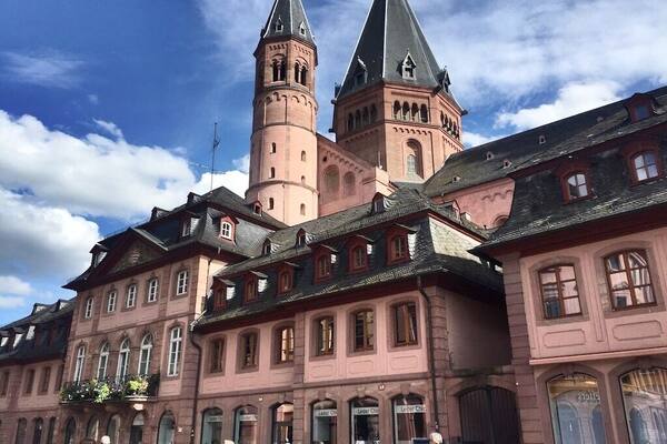 Mainz is a German city on the Rhine River. It’s known for its old town, with half-timbered houses and medieval market squares. In the center, the Marktbrunnen is a Renaissance fountain with red columns. Nearby, a distinctive octagonal tower tops the Romanesque Mainz Cathedral, built of deep red sandstone. The Gutenberg Museum honors the inventor of the printing press with exhibits, including 2 of his original bibles.