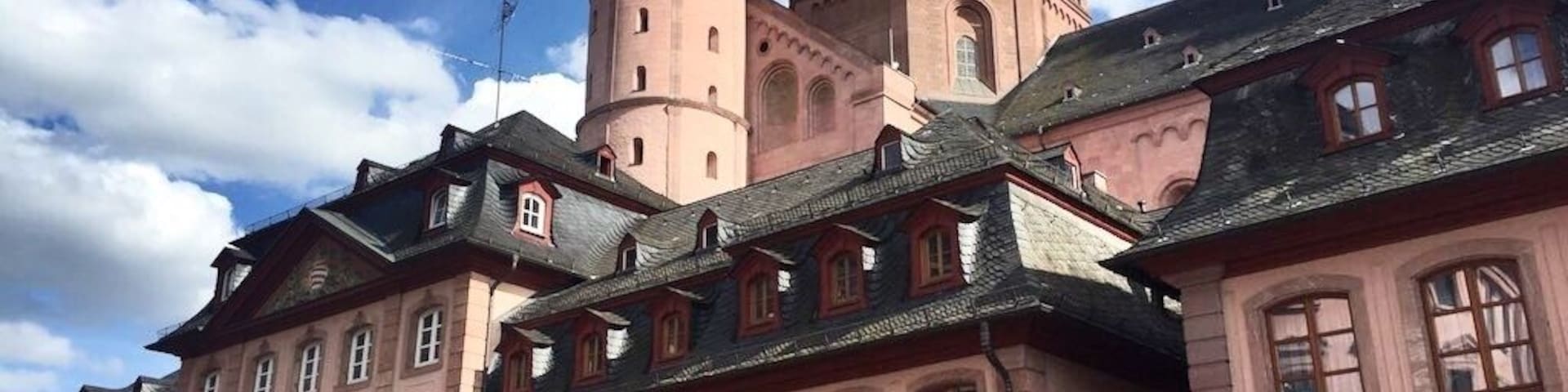 Mainz is a German city on the Rhine River. It’s known for its old town, with half-timbered houses and medieval market squares. In the center, the Marktbrunnen is a Renaissance fountain with red columns. Nearby, a distinctive octagonal tower tops the Romanesque Mainz Cathedral, built of deep red sandstone. The Gutenberg Museum honors the inventor of the printing press with exhibits, including 2 of his original bibles.