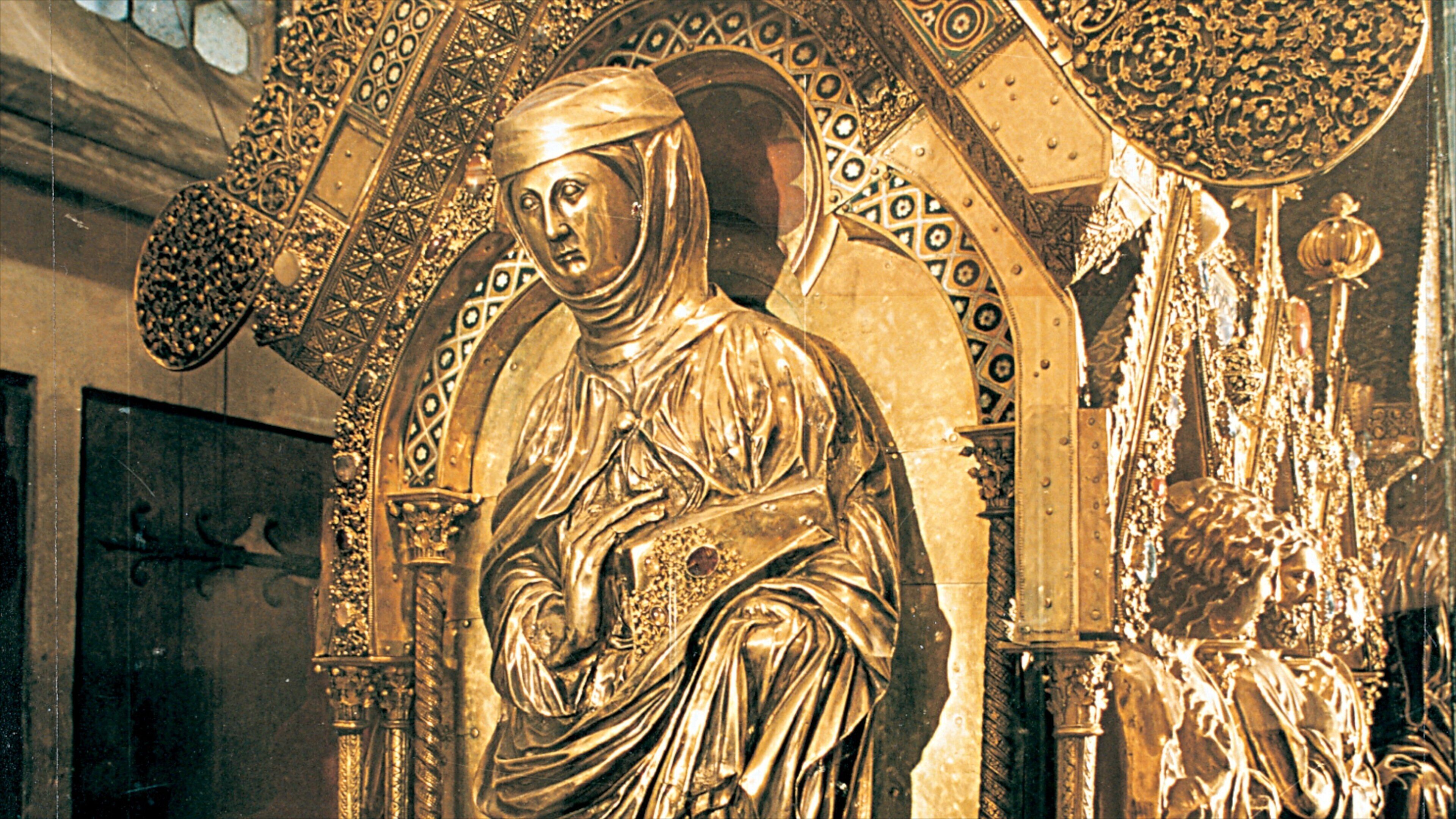 A golden statue of a robed figure with intricate architectural details in the background.