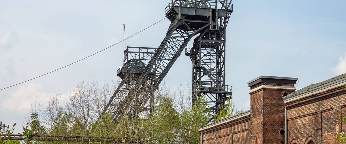 A large metal structure with a rotating mechanism, a brick building, and some trees.