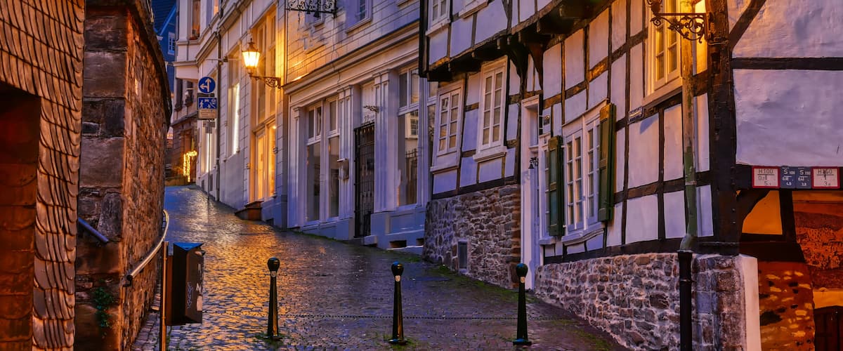 A cobblestone street with traditional half-timbered buildings, a street sign, and a lamppost.