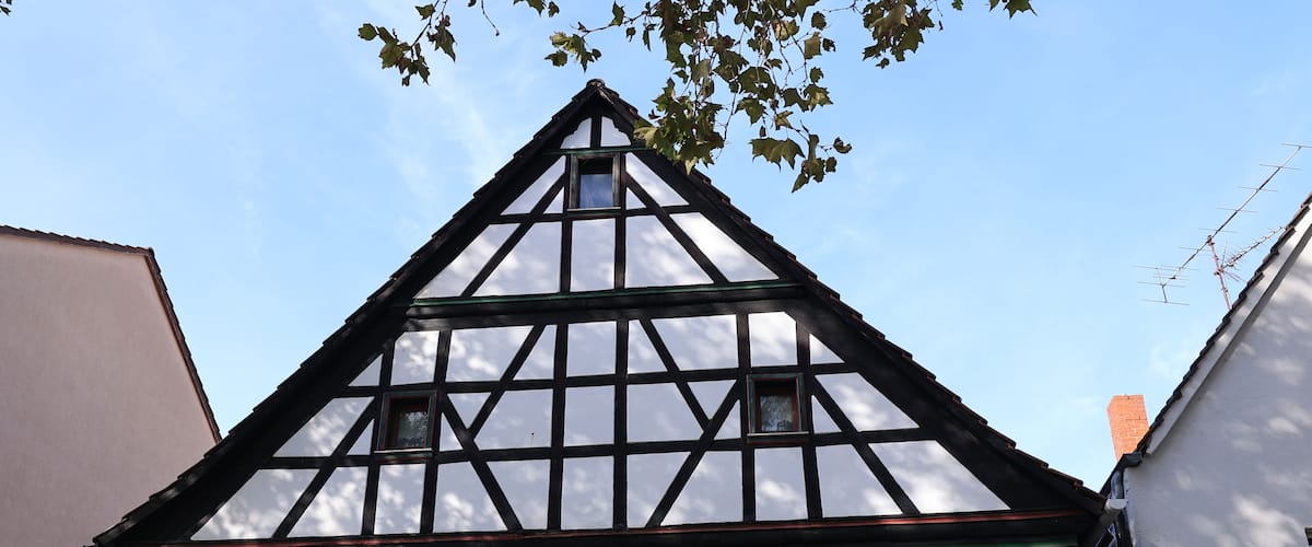 A half-timbered house with a steeply pitched roof, dormer windows, and flower boxes on the ground floor.