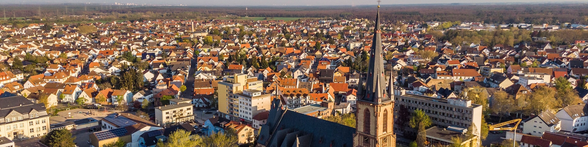 Beautiful morning top view of the central part of Viernheim. Old catholic cathedral. Orange tiled roofs of houses. Germany.