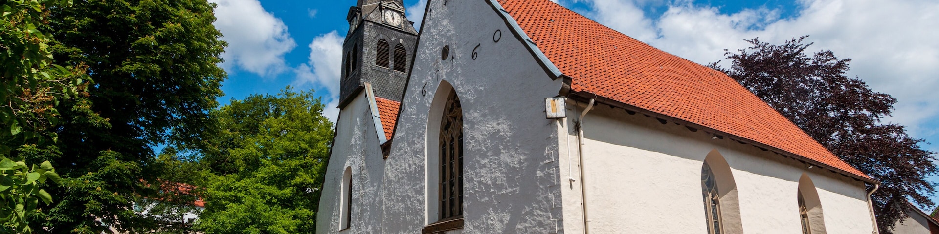 A church with a tall steeple and a red-tiled roof.
