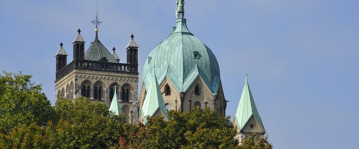 A historic church with a large dome and multiple spires, surrounded by lush trees.