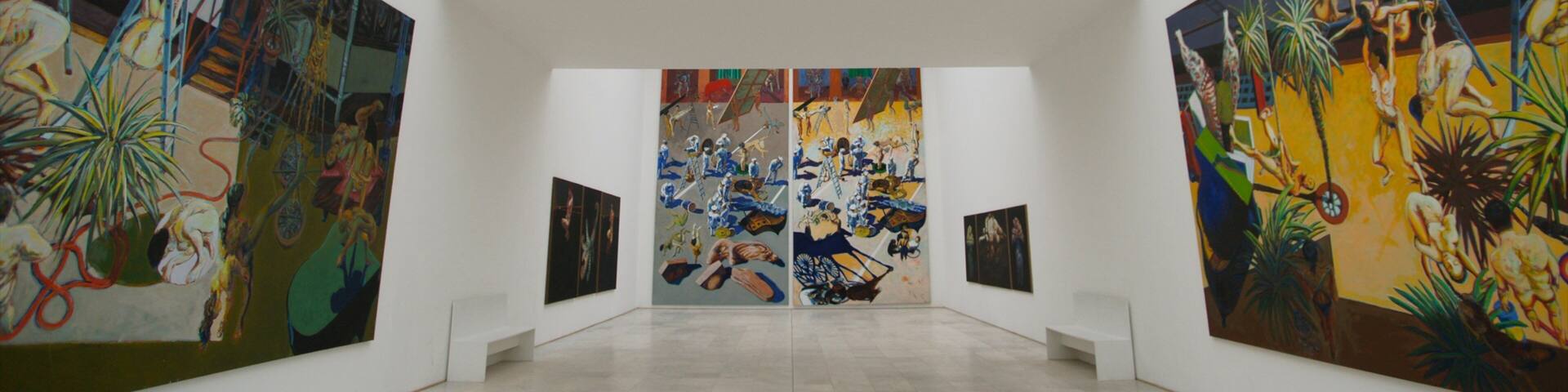 An art gallery with large paintings on the walls and a skylight above.