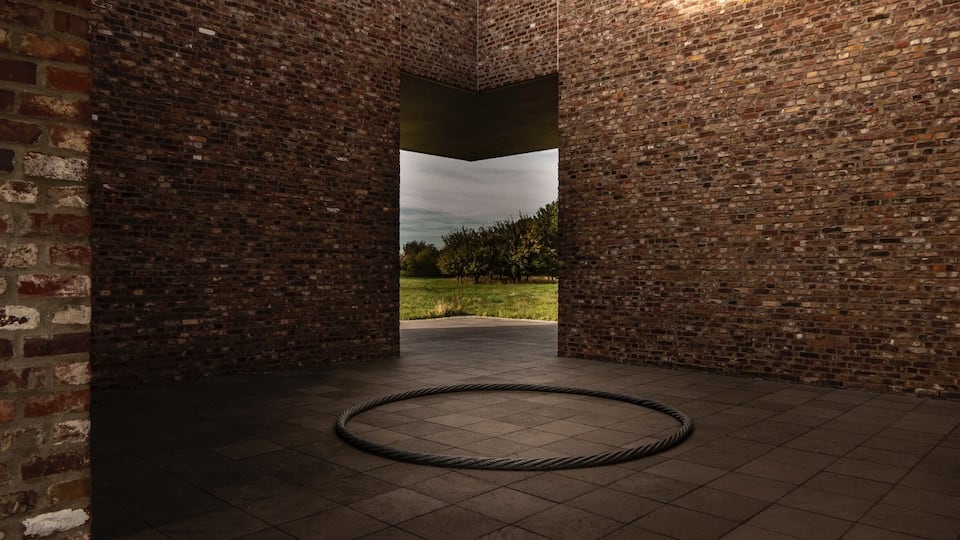 A brick-walled corridor with a circular object on the floor and a view of a grassy area through an opening.