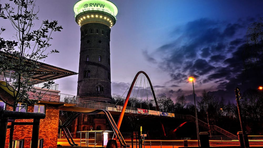 A water tower, a bridge, and a roller coaster at dusk.