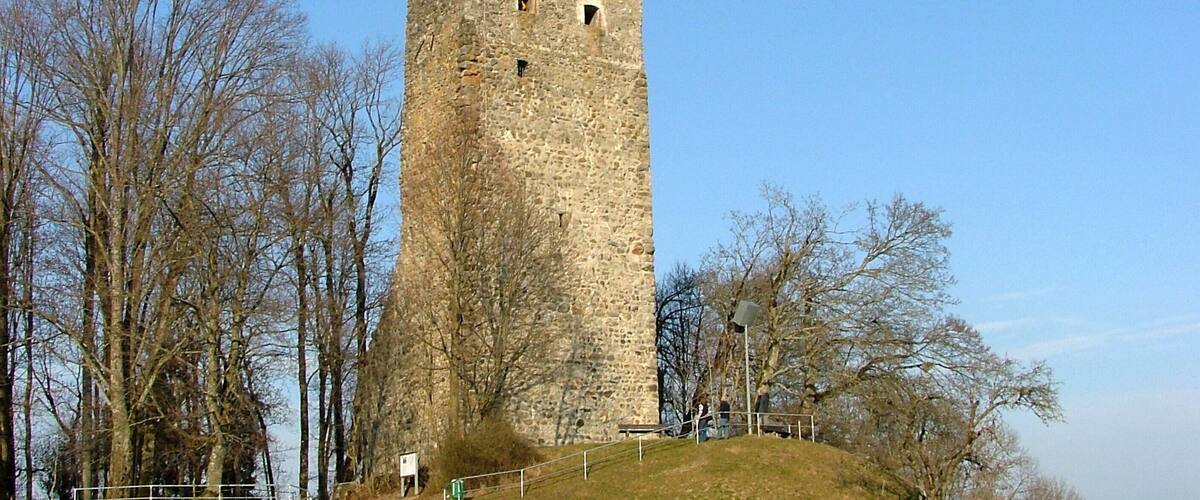 A tall stone tower with a steep, narrow staircase leading up to it, surrounded by leafless trees and a clear sky.