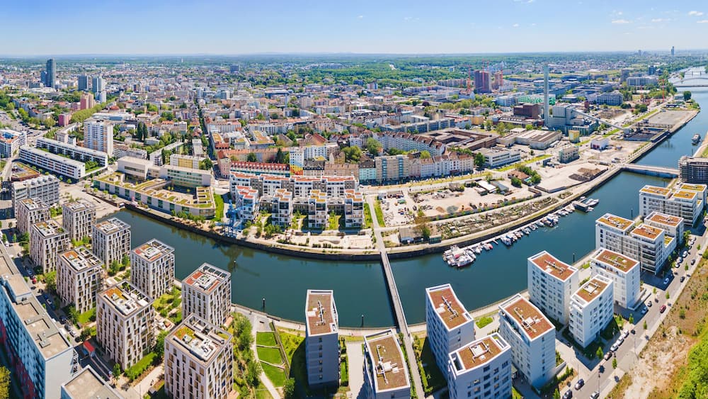 A river winding through a city with modern buildings and a bridge.