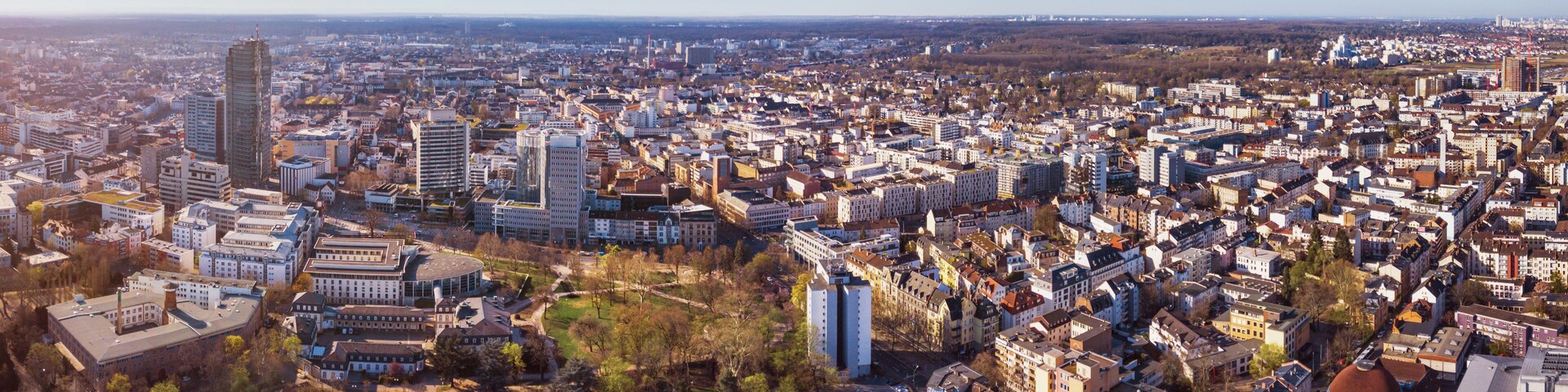 A panoramic view of a densely populated city with numerous buildings, including modern skyscrapers and older structures, and a mix of residential and commercial areas.