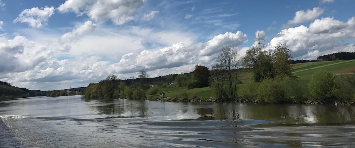 A river with a cloudy sky and green landscape.