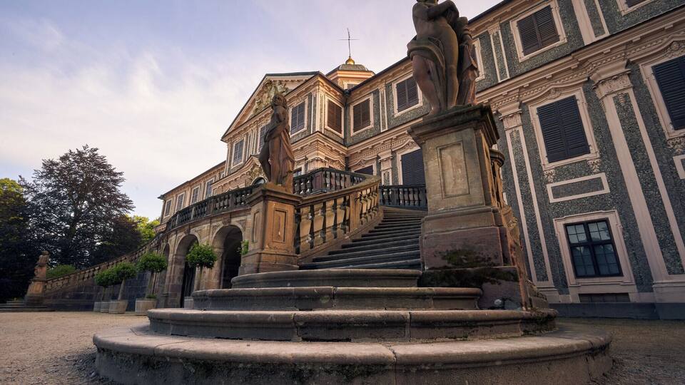 A historic building with a grand staircase and classical statues.