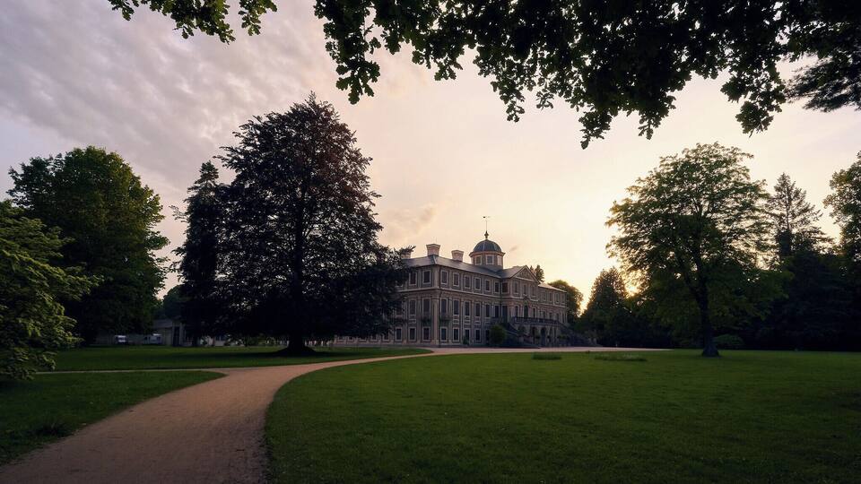 A large building with a dome, surrounded by a well-maintained lawn and trees.