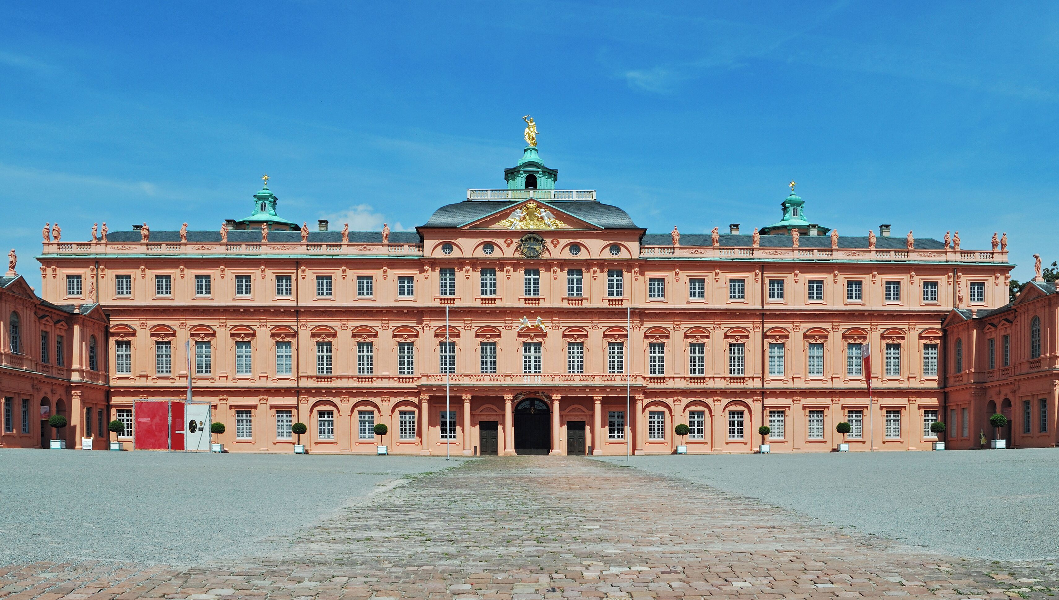 A large, ornate building with a central dome and statues on the roof.