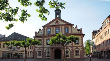 A historic building with a clock tower, surrounded by cobblestone streets and trees.