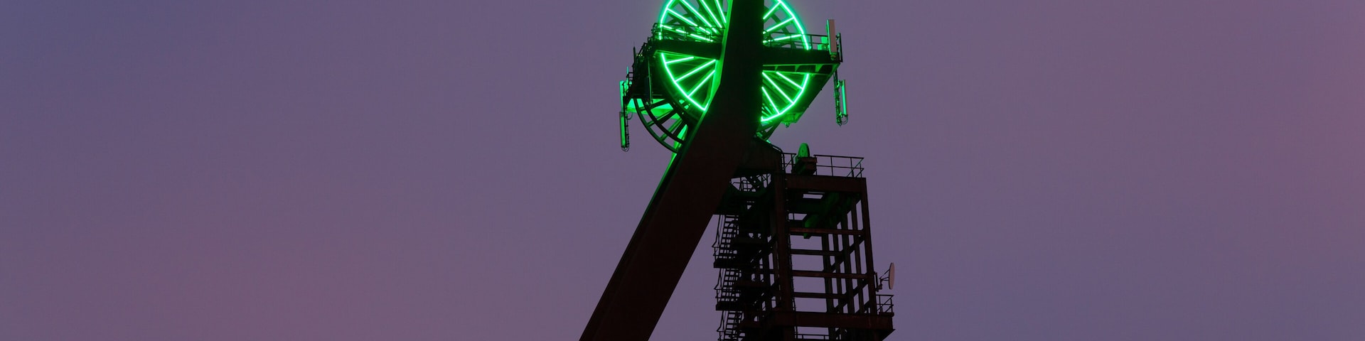 A Ferris wheel with green lights against a purple sky.