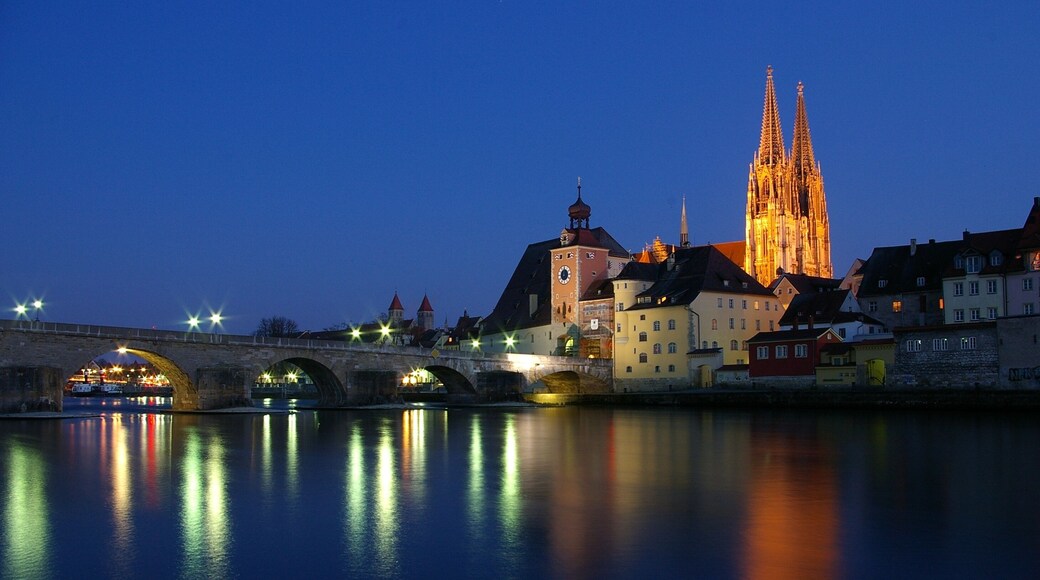 The Stone Bridge in Regensburg over the Danube at sunset with the Regensburg Cathedral in the background.