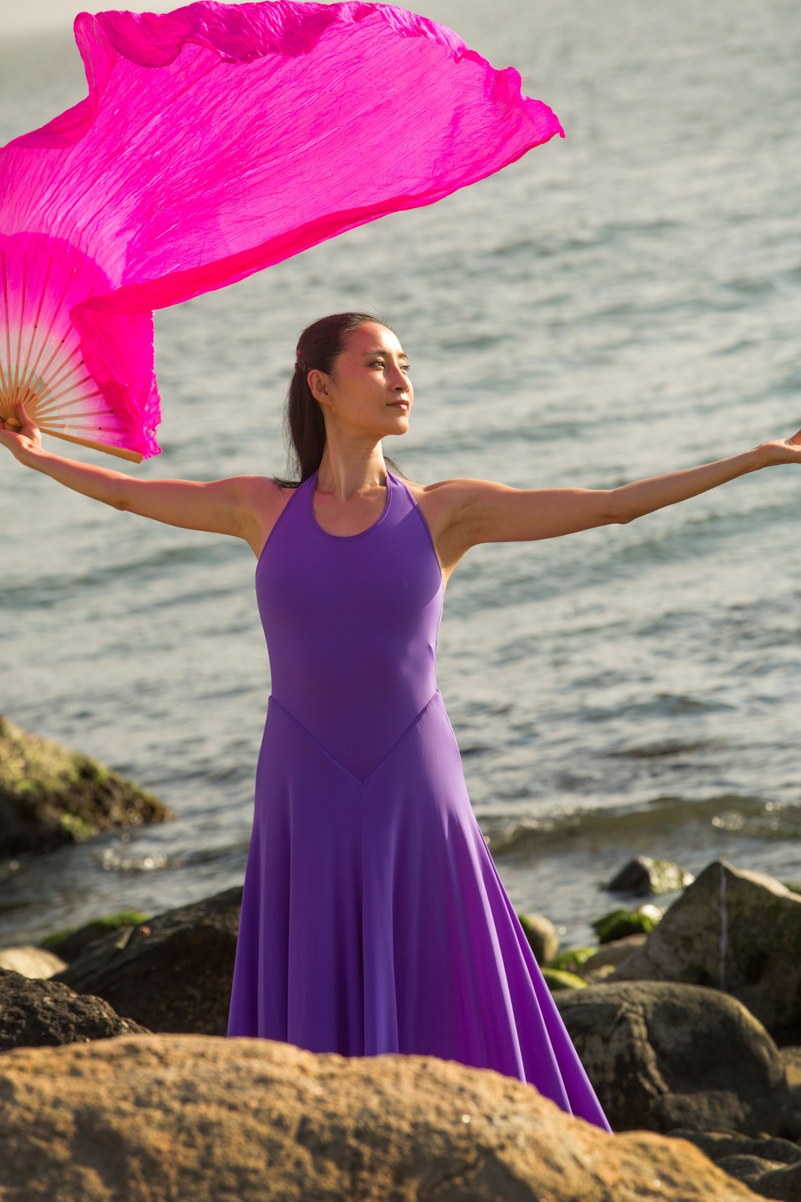 Adult woman dancing on a rocky beach in Connecticut.