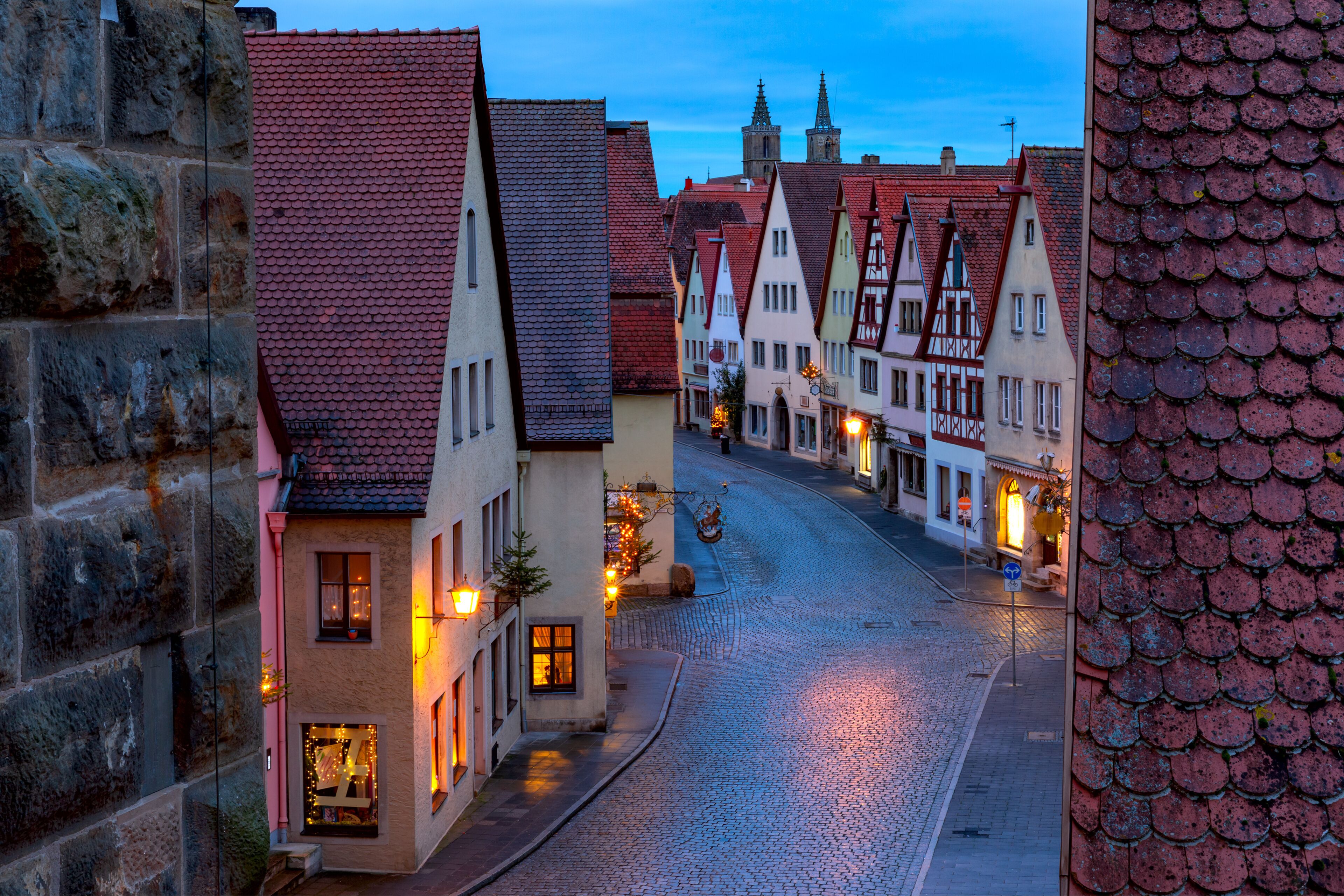 A cobblestone street lined with traditional half-timbered houses and a stone wall on the left.
