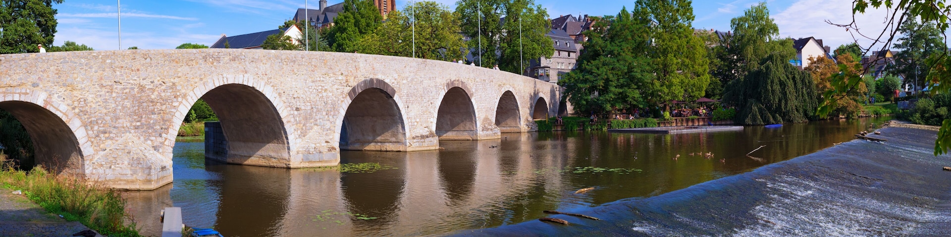 A stone bridge over a river with a town in the background.
