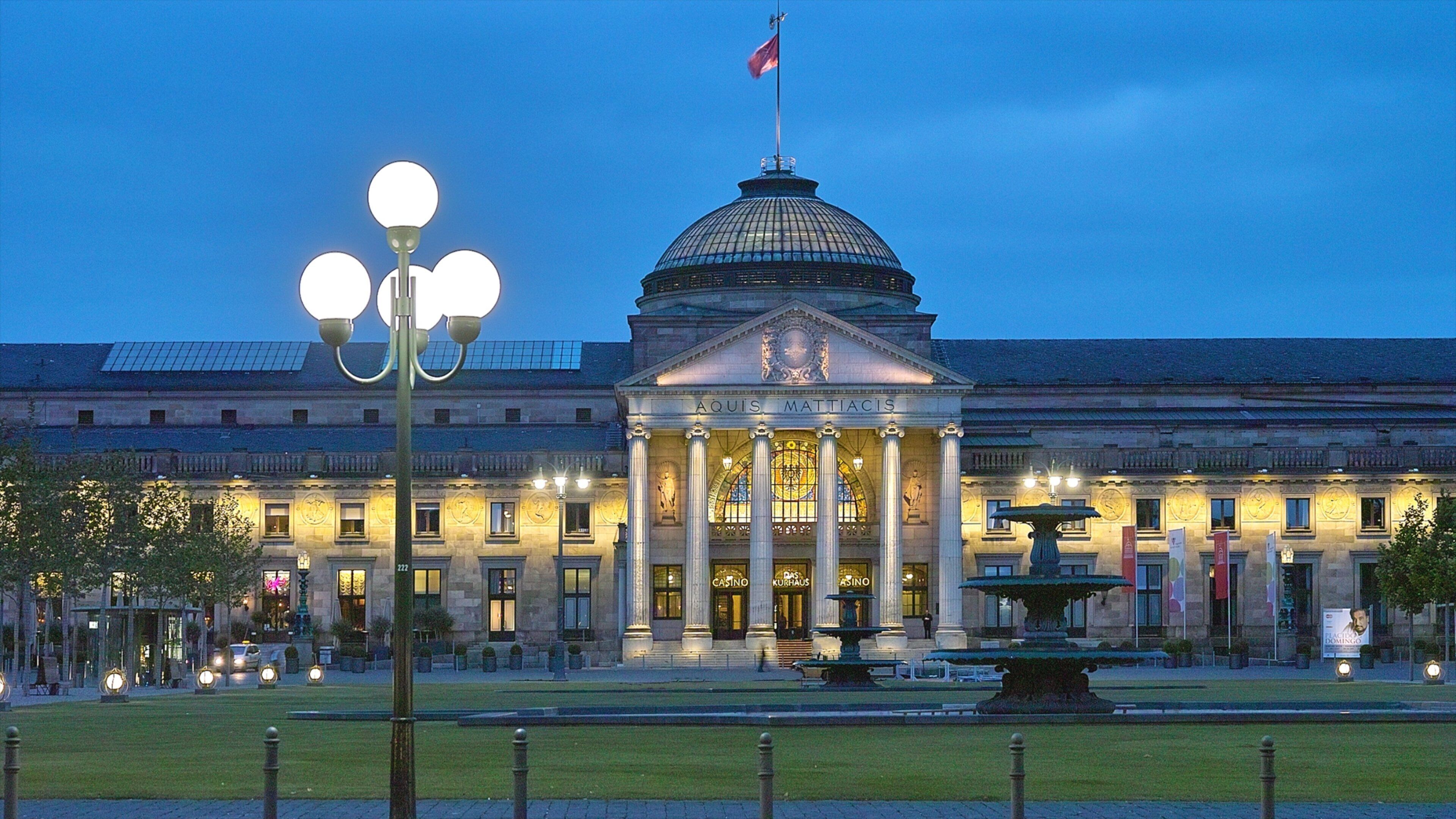 A grand building with a dome and columns, illuminated at dusk.