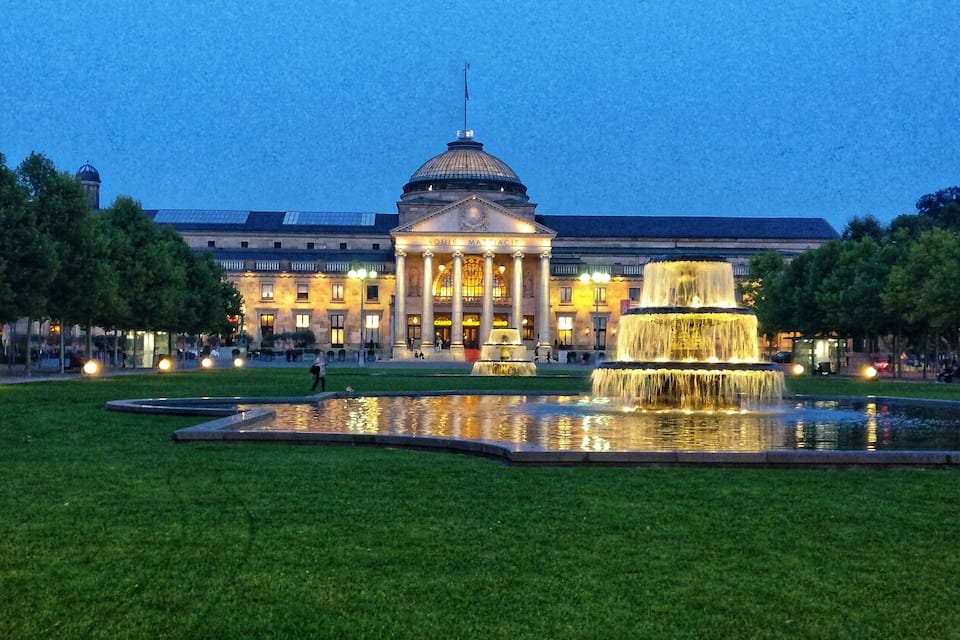 Een statig gebouw met een koepel en kolommen, een grote fontein en verzorgde gazons.