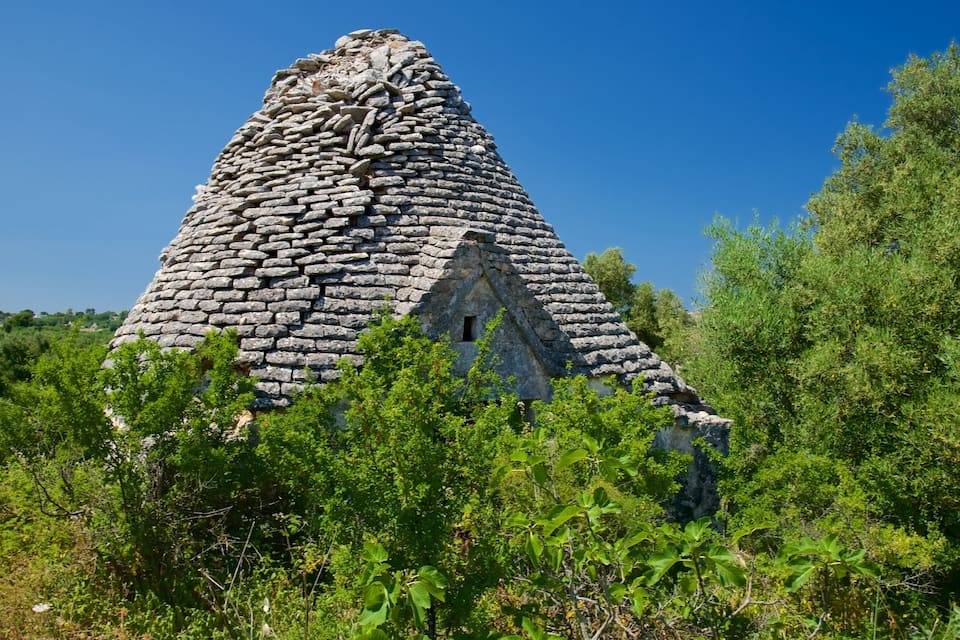 A stone pyramid-like structure surrounded by greenery.