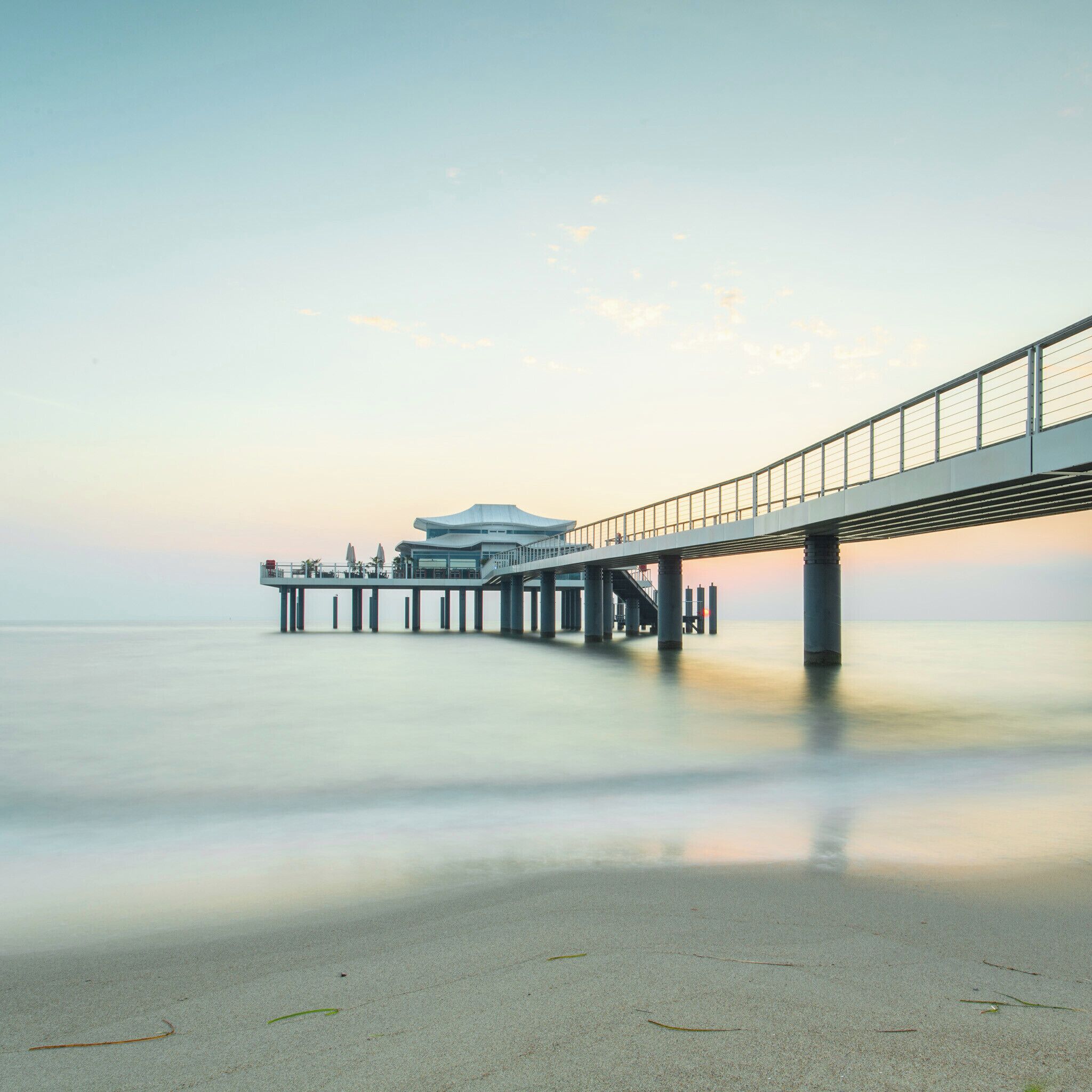 A pier extending into calm waters with a modern building at the end.