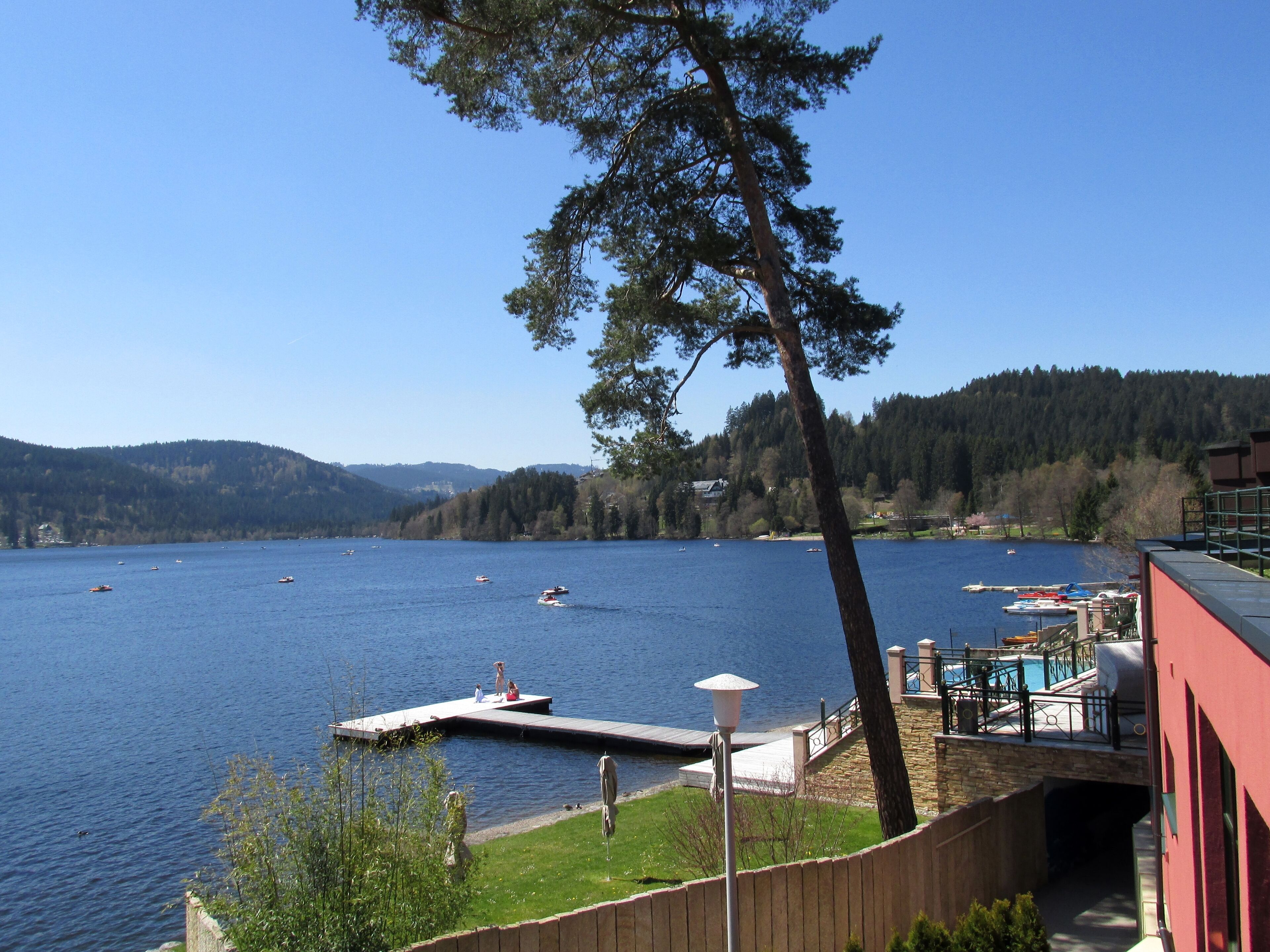 A lake with boats, a dock, and a building with a red exterior.