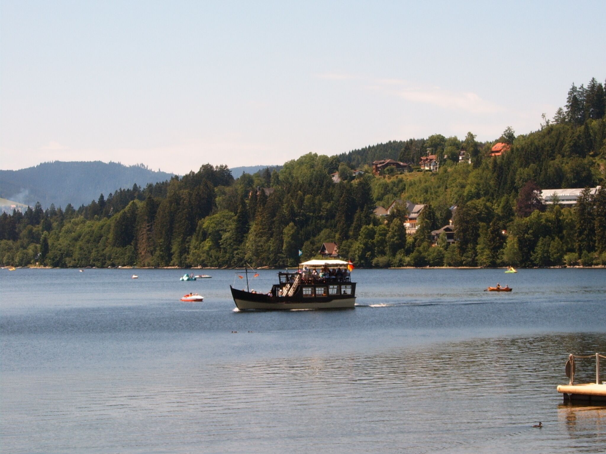 A lake with a boat in the foreground and several smaller boats in the background.