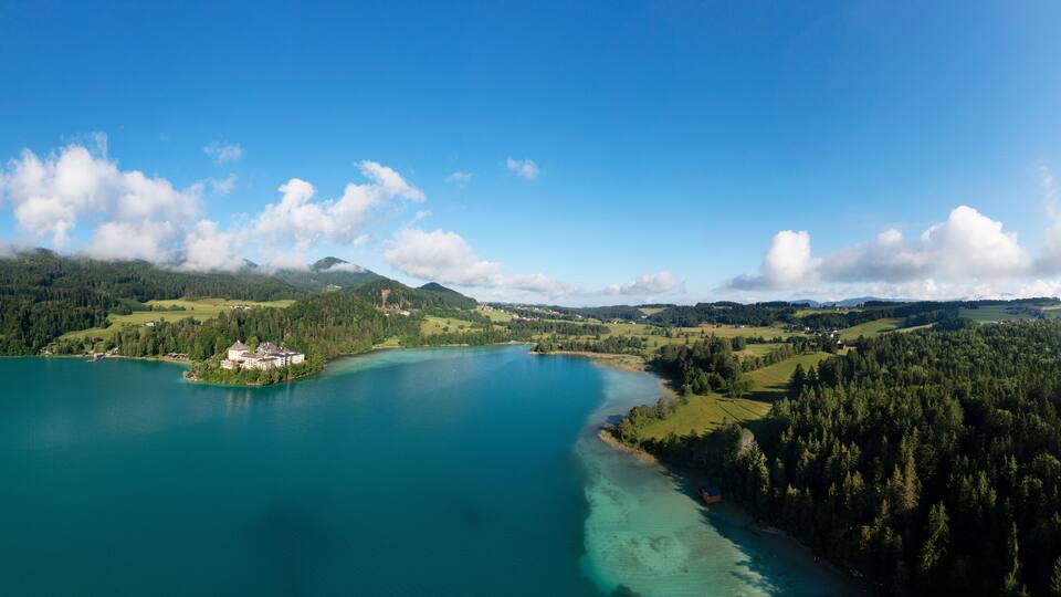 A lake surrounded by forested hills and a small island with a building.