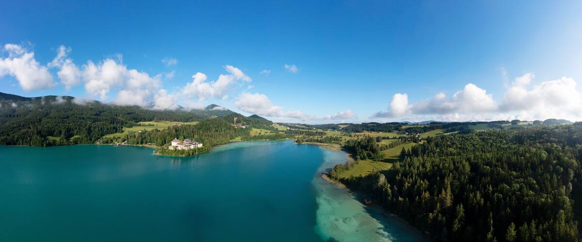 A lake surrounded by forested hills and a small island with a building.