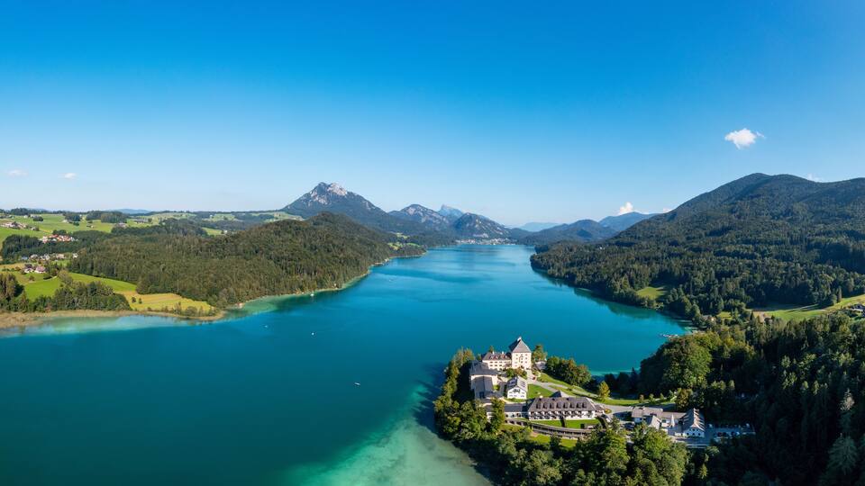 A lake surrounded by mountains and a castle.
