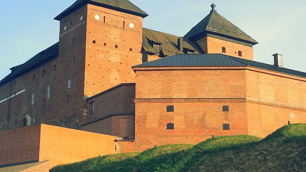 Un grand château en briques, doté de nombreuses tours et d’une tour centrale particulièrement imposante.